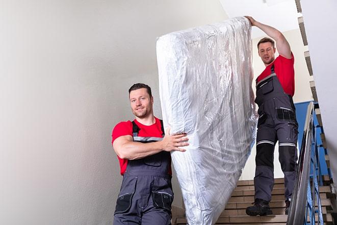 two workers carrying a heavy box spring out of a bedroom in Huntingdon